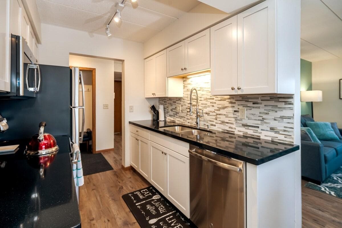 Updated kitchen with new cabinets, stainless steel appliances, and tiled backsplash.